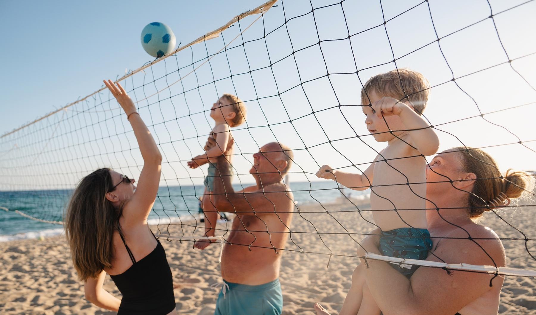 a group of people playing volleyball on a beach